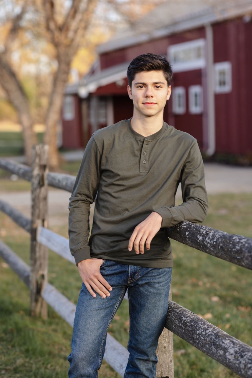 Aleksander Bobkov standing beside a wooden fence outdoors